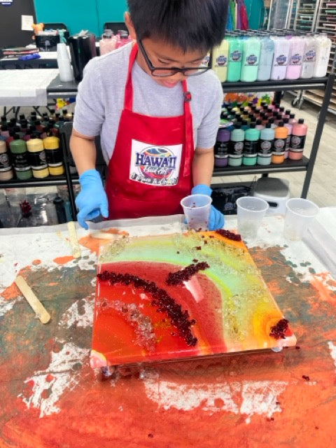 Camper adding fire glass to a fluid art canvas
