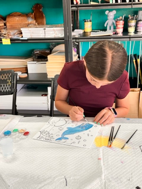 A camper carefully painting during a supplemental session
