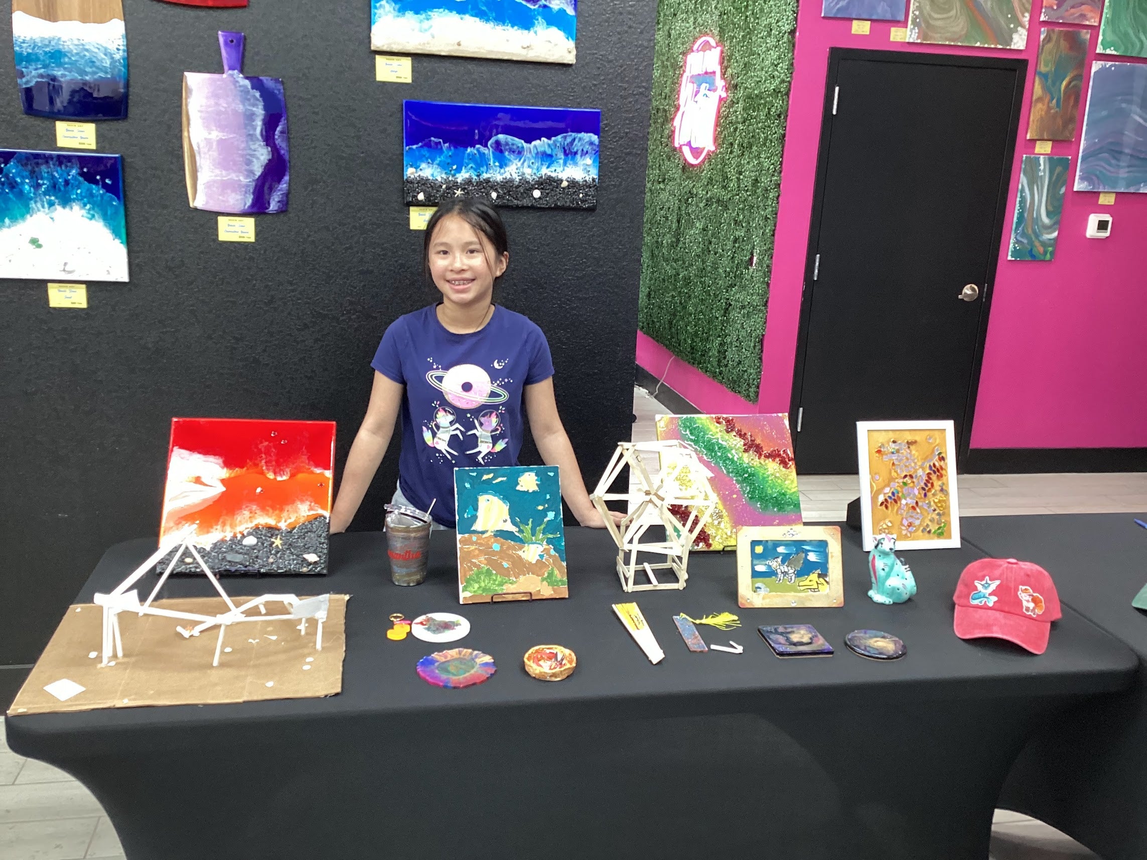 Camper standing proudly behind her full table of artwork from the 10-day Signature Camp showcase